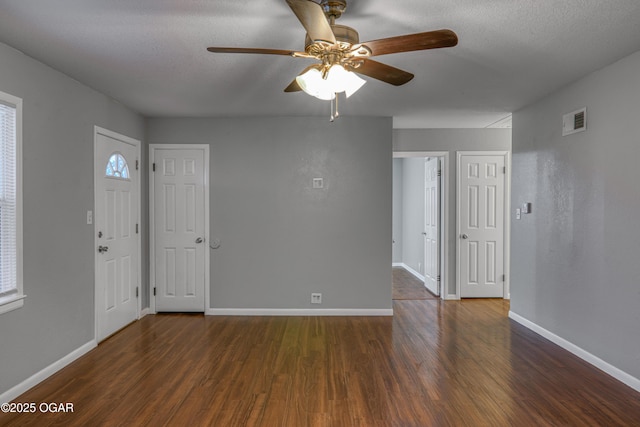 foyer featuring dark wood-type flooring, visible vents, a textured ceiling, and baseboards