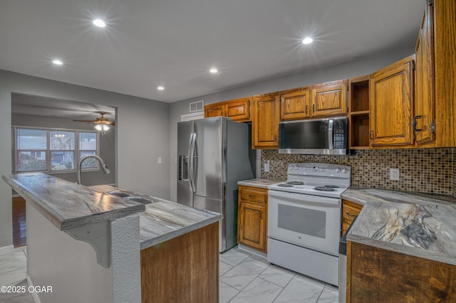 kitchen featuring brown cabinetry, appliances with stainless steel finishes, marble finish floor, a kitchen island with sink, and a sink