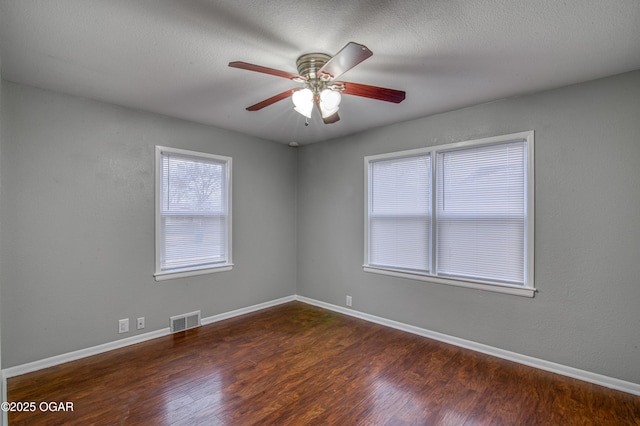 spare room with baseboards, visible vents, a ceiling fan, wood finished floors, and a textured ceiling