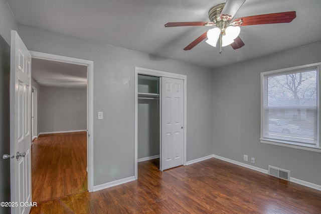 unfurnished bedroom with wood finished floors, a ceiling fan, visible vents, baseboards, and a closet