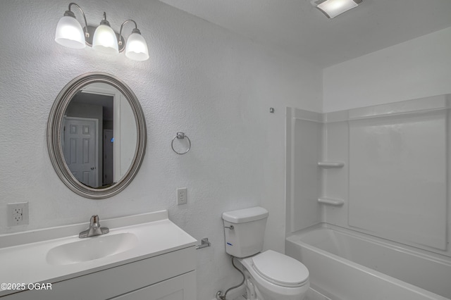 bathroom featuring a textured wall, vanity, and toilet