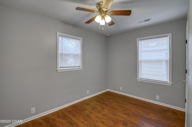 spare room with visible vents, ceiling fan, baseboards, and wood finished floors