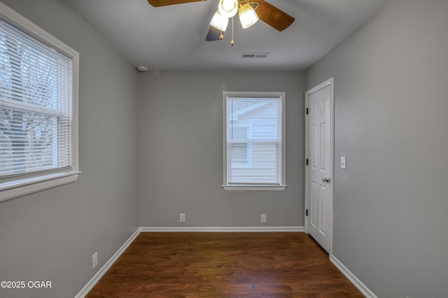 unfurnished room featuring a wealth of natural light, wood finished floors, visible vents, and baseboards