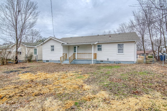 rear view of house with covered porch, a shingled roof, crawl space, and fence