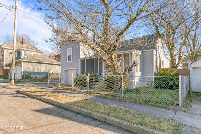 view of front of home with driveway, a fenced front yard, an attached garage, and a sunroom