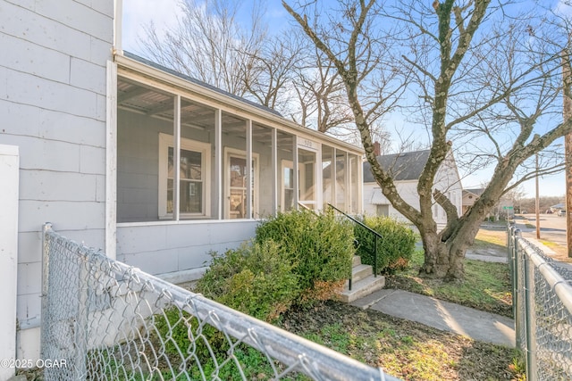 view of side of property featuring a sunroom and fence