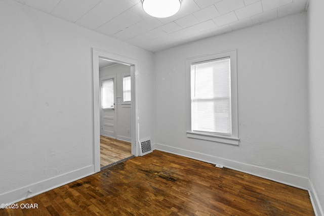 spare room featuring visible vents, dark wood finished floors, and baseboards