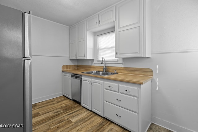 kitchen featuring tile walls, appliances with stainless steel finishes, dark wood-type flooring, white cabinets, and a sink