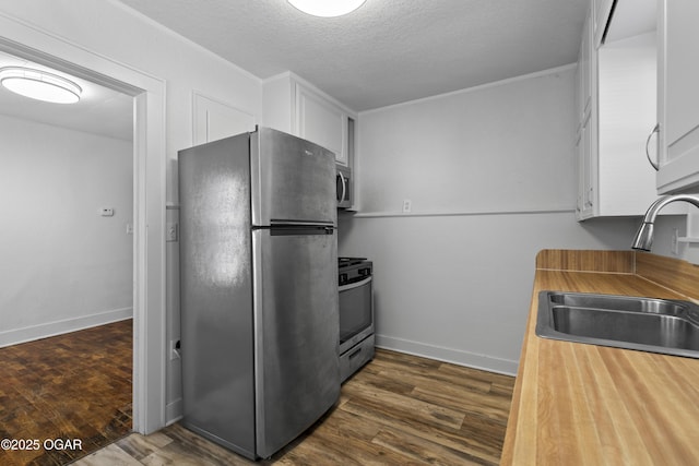 kitchen with dark wood-style floors, stainless steel appliances, a sink, and white cabinetry