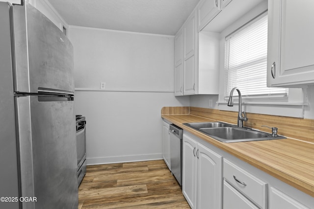 kitchen with stainless steel appliances, white cabinetry, a sink, and wood finished floors