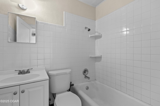 bathroom with tile walls, a textured wall, toilet, washtub / shower combination, and vanity