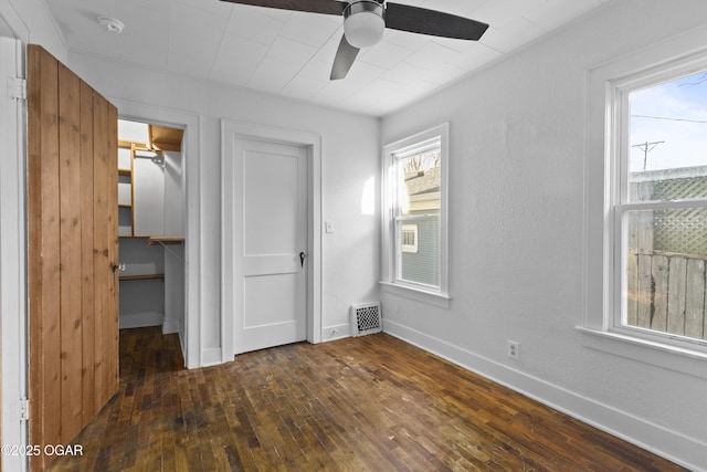 unfurnished bedroom with baseboards, visible vents, dark wood-style floors, a walk in closet, and a closet