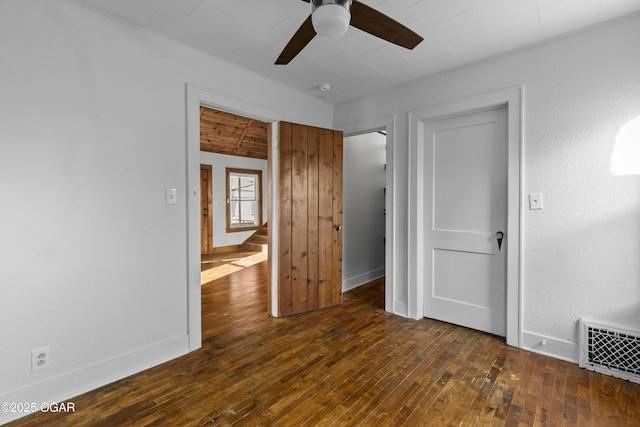 empty room with dark wood-style floors, baseboards, visible vents, and ceiling fan