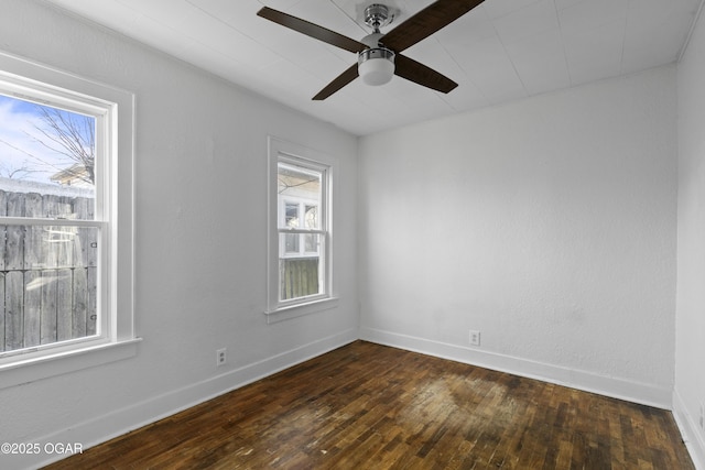 spare room with ceiling fan, dark wood-type flooring, and baseboards