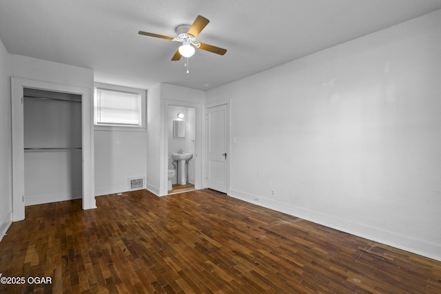 unfurnished bedroom with visible vents, baseboards, wood-type flooring, ensuite bathroom, and a sink