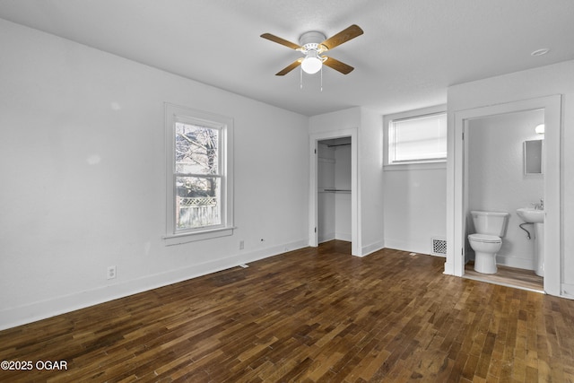 unfurnished bedroom featuring baseboards, ceiling fan, ensuite bath, and hardwood / wood-style floors