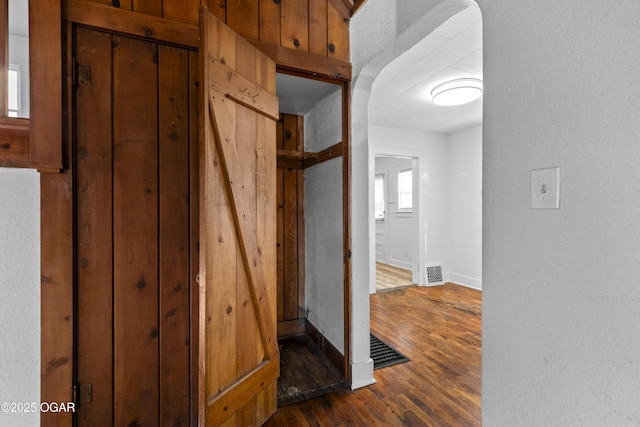 hallway with dark wood-style flooring, visible vents, and baseboards