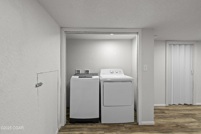 laundry area with a textured wall, a textured ceiling, wood finished floors, laundry area, and independent washer and dryer