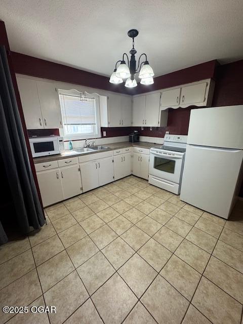 kitchen with pendant lighting, white cabinetry, a sink, a textured ceiling, and white appliances