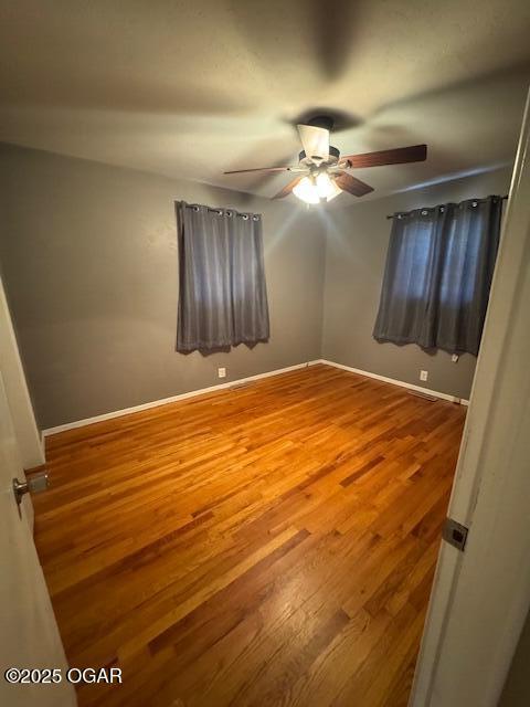 unfurnished bedroom with a ceiling fan, baseboards, and wood finished floors