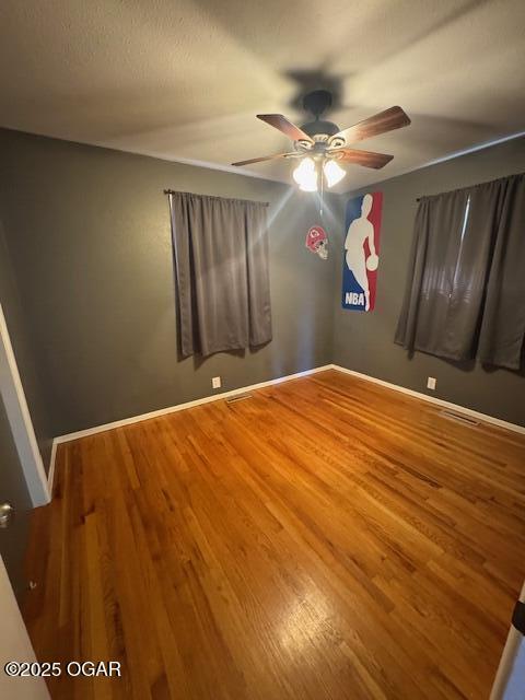 unfurnished bedroom featuring visible vents, ceiling fan, baseboards, and wood finished floors