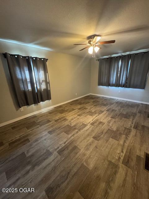 spare room with ceiling fan, dark wood-type flooring, a textured ceiling, and baseboards