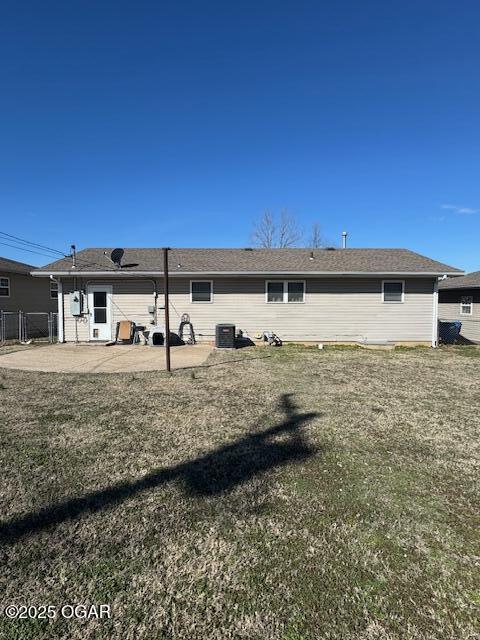 rear view of house with a patio, a lawn, and fence