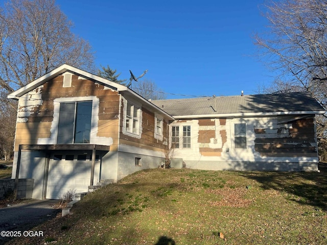 view of front of home featuring driveway, an attached garage, cooling unit, and a front yard