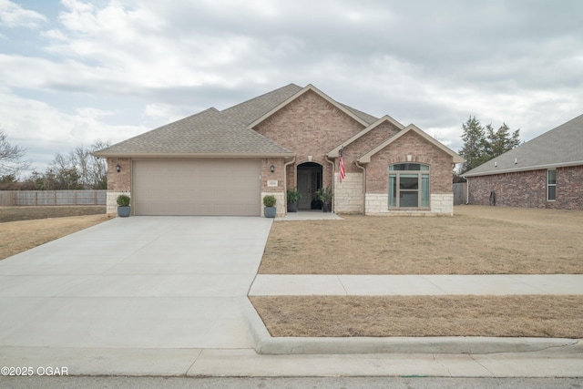 view of front of home featuring a garage, brick siding, concrete driveway, roof with shingles, and a front yard