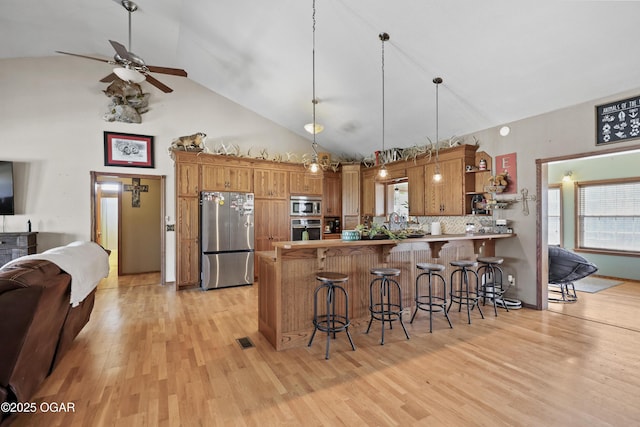 kitchen featuring light wood-type flooring, a breakfast bar, a peninsula, appliances with stainless steel finishes, and open floor plan