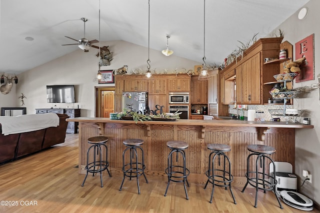 kitchen with light wood-style flooring, open shelves, a sink, appliances with stainless steel finishes, and brown cabinetry