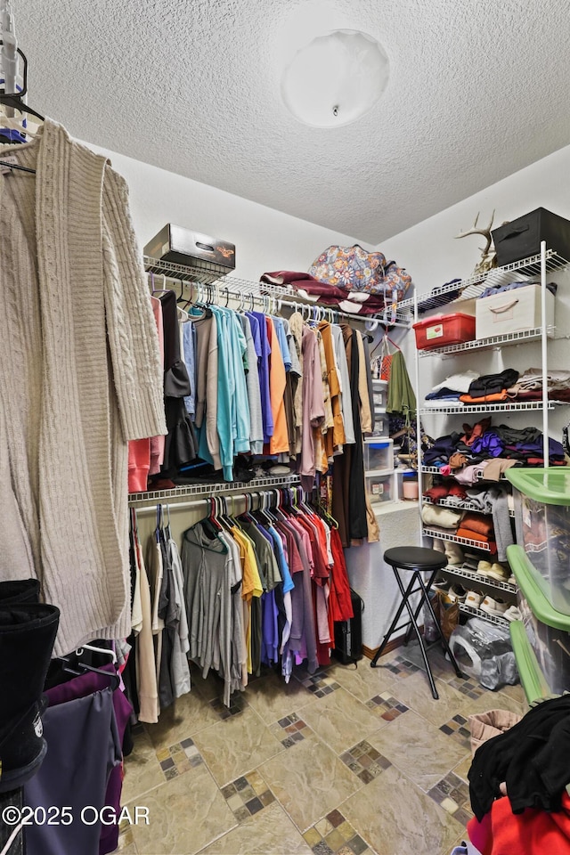 walk in closet featuring stone finish flooring