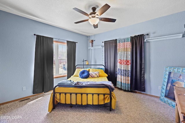 carpeted bedroom featuring visible vents, a ceiling fan, a textured ceiling, baseboards, and a textured wall