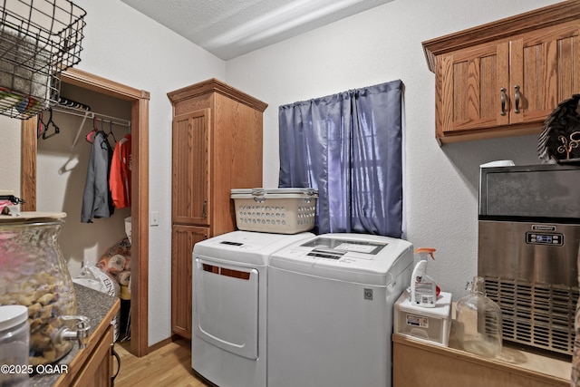 laundry room with cabinet space, washing machine and dryer, and light wood finished floors