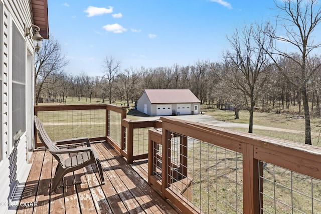 wooden terrace with a detached garage, a rural view, a lawn, and an outdoor structure