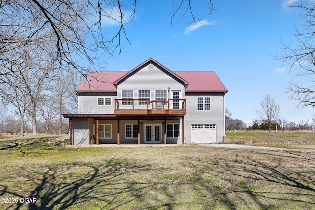 rear view of property with a wooden deck, a lawn, french doors, metal roof, and an attached garage