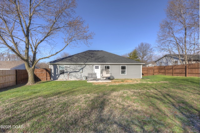 back of house featuring a yard, a fenced backyard, and roof with shingles