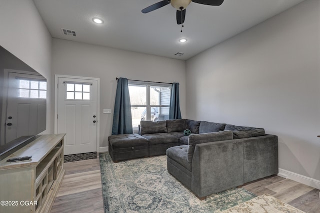 living room featuring light wood-type flooring, visible vents, and a ceiling fan