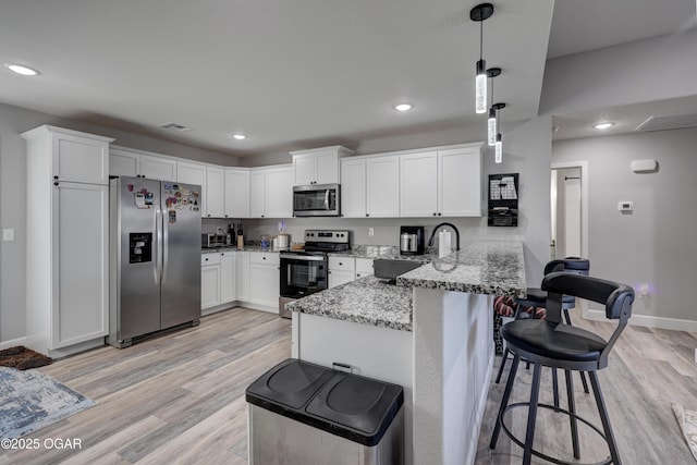 kitchen with visible vents, a peninsula, a sink, appliances with stainless steel finishes, and white cabinetry