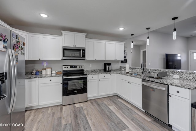 kitchen featuring a sink, light wood-style floors, appliances with stainless steel finishes, a peninsula, and white cabinets