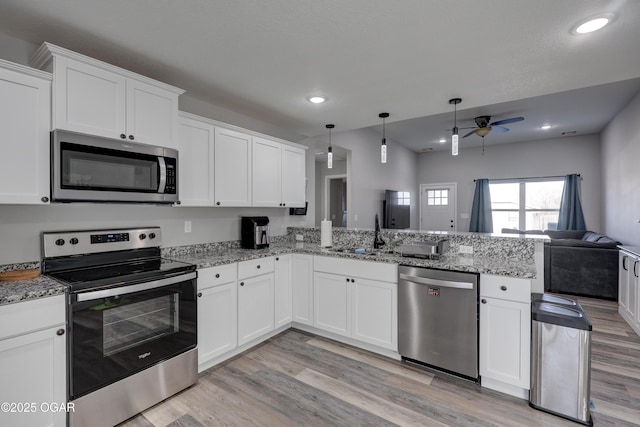 kitchen featuring a peninsula, ceiling fan, stainless steel appliances, white cabinets, and open floor plan