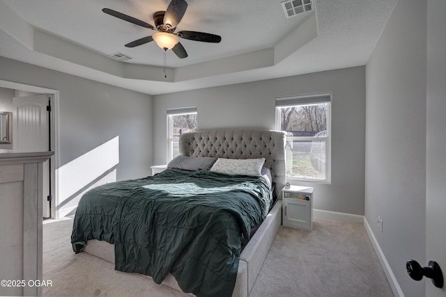 bedroom with a raised ceiling, visible vents, and light carpet