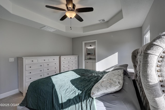 bedroom with a raised ceiling, baseboards, visible vents, and light carpet