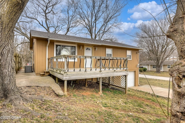 rear view of house with a garage, concrete driveway, a wooden deck, and central air condition unit