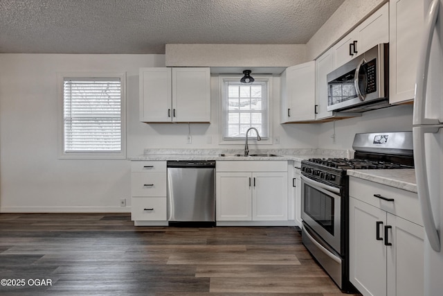 kitchen featuring stainless steel appliances, dark wood-type flooring, a sink, and white cabinetry