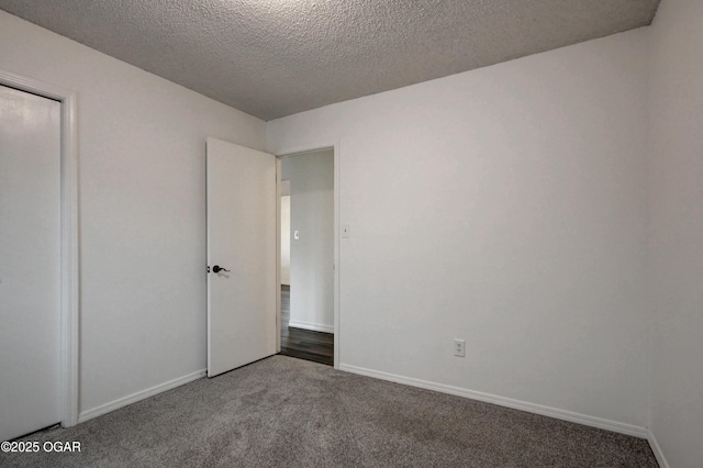 unfurnished bedroom featuring carpet, a textured ceiling, and baseboards