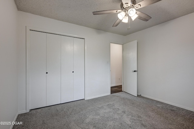 unfurnished bedroom featuring carpet floors, a textured ceiling, baseboards, and a closet