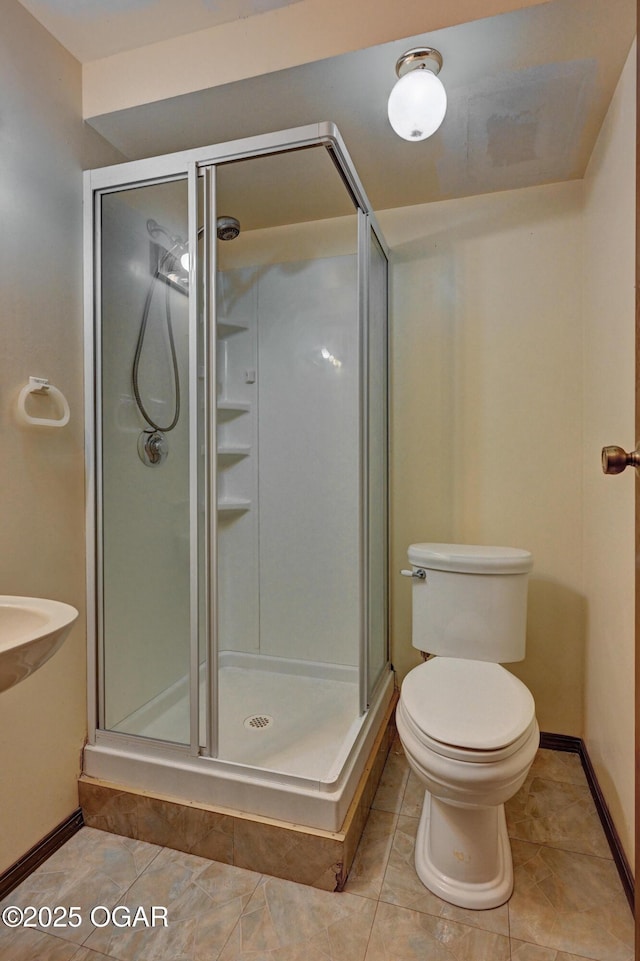 full bath with toilet, a stall shower, baseboards, and tile patterned floors