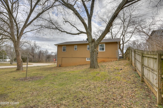 view of side of home featuring fence and a lawn