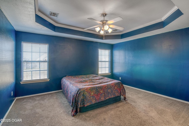 carpeted bedroom featuring visible vents, multiple windows, and a tray ceiling